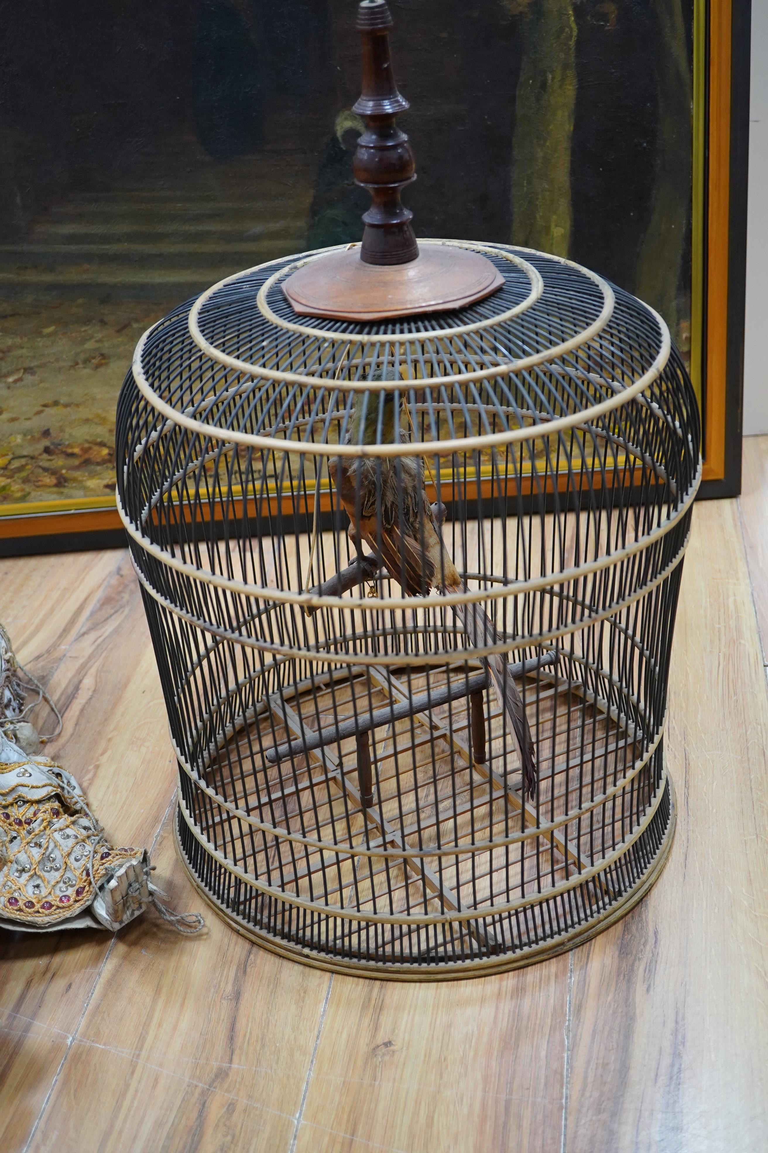 A Thai painted wood puppet, with sequined fabric costume and a wire and rattan circular bird cage, 65cm. Condition - fair